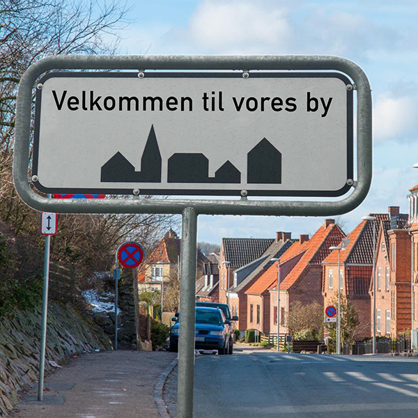 Byskilt med teksten "Velkommen til vores by"