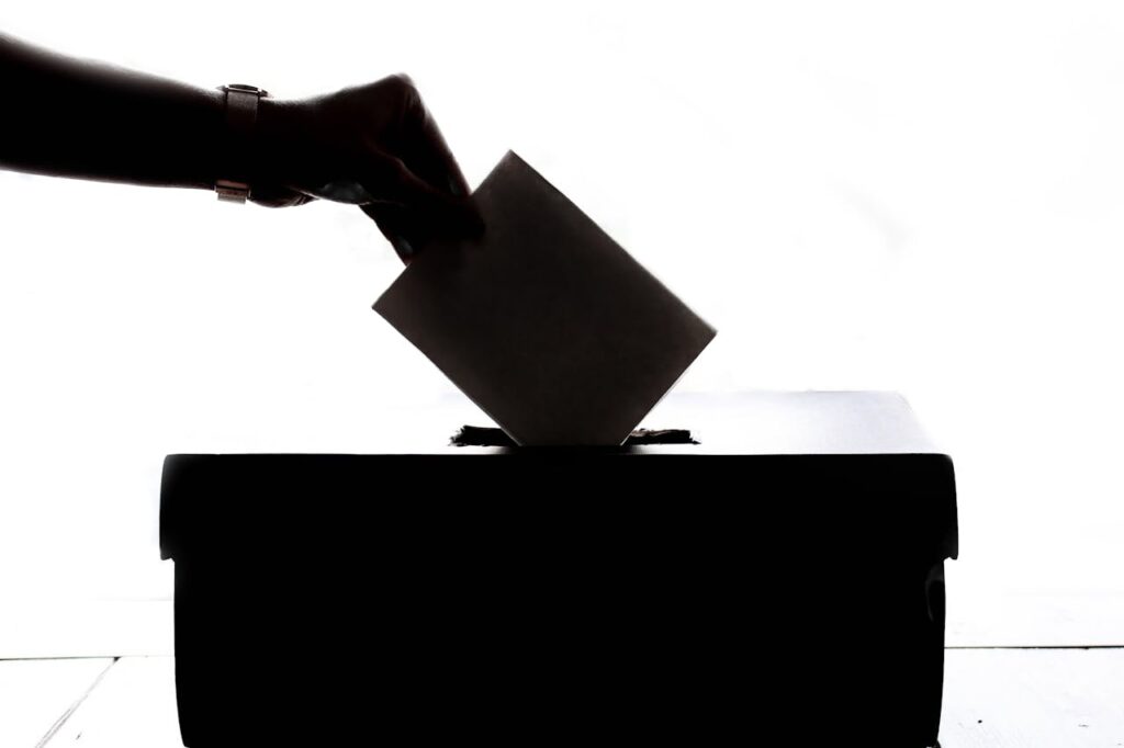 pexels-photo-1550337 Silhouette of a hand placing a vote into a ballot box, symbolizing democracy.